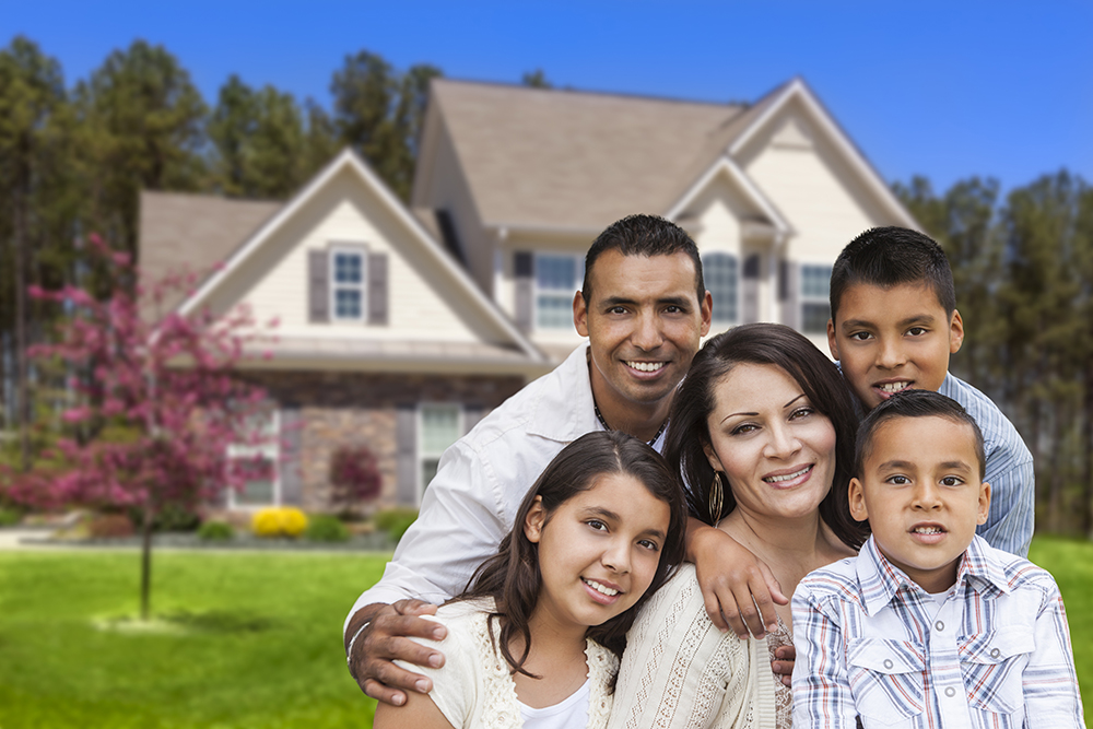 happy hispanic family portrait in front of beautiful house.